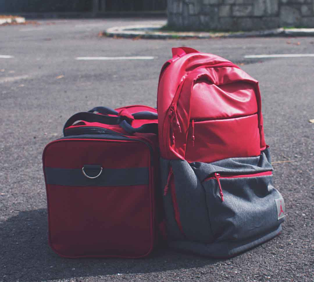 Red and Gray Backpack Beside Red Duffel Bag