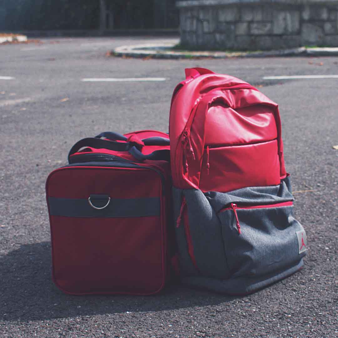 Red and Gray Backpack Beside Red Duffel Bag