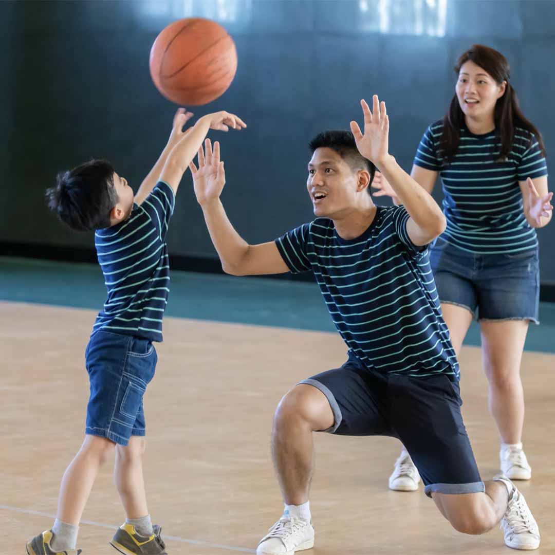 adults playing basketball with a kid