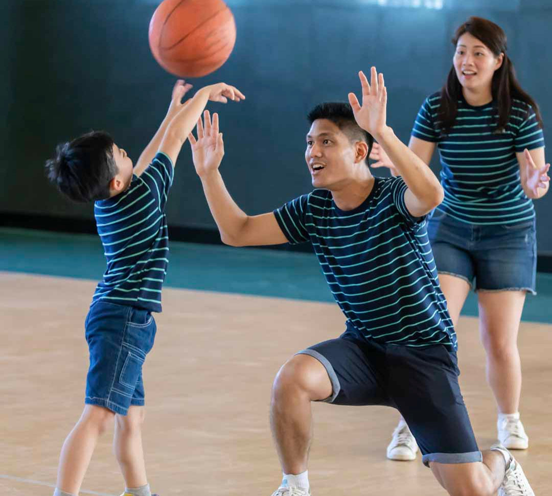 adults playing basketball with a kid